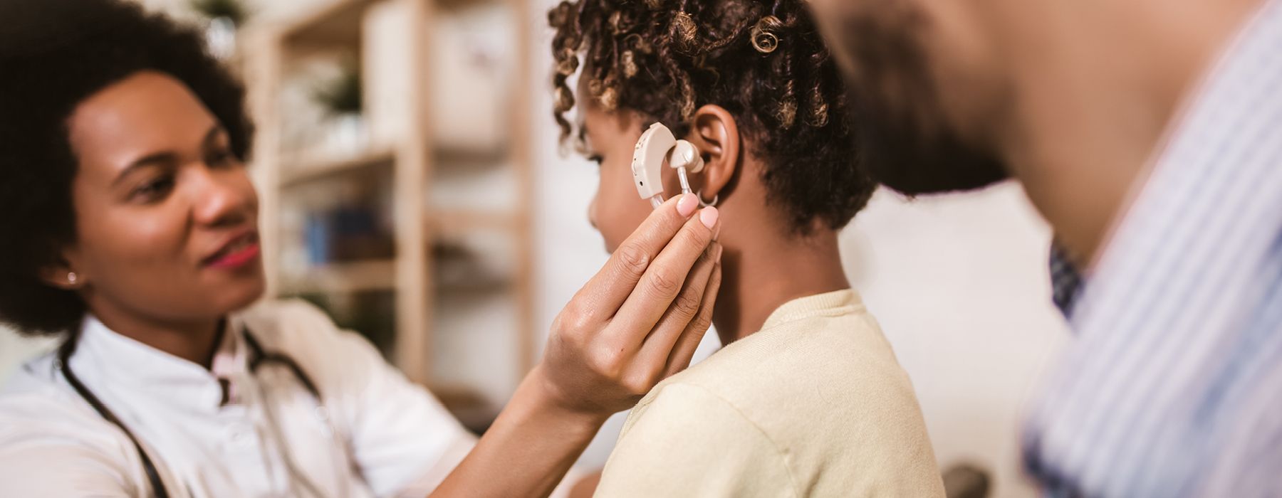 Medical practitioner checking a child's hearing aid
